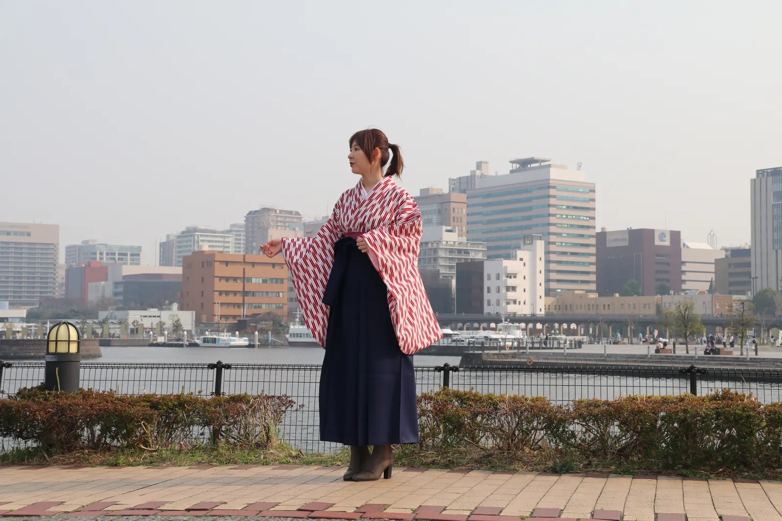 A woman in hakama with the Yokohama waterfront near Yamashita Park behind her