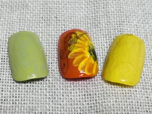 オレンジ色のベースにヒマワリとラインアートが描かれたチップと、淡いグリーン、イエローのチップが並んでいる様子